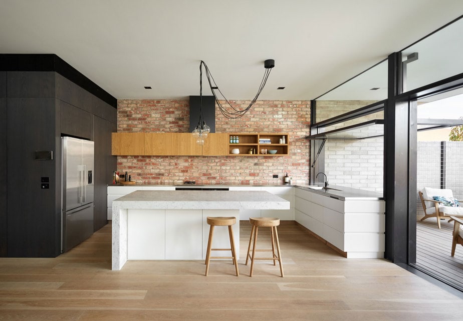 Smarter Bathrooms and Kitchens - a bright kitchen with wooden floor, elegant full wall cabinet, marble top, and brick wall. Beautiful kitchen designs built by kitchen renovations Melbourne specialist