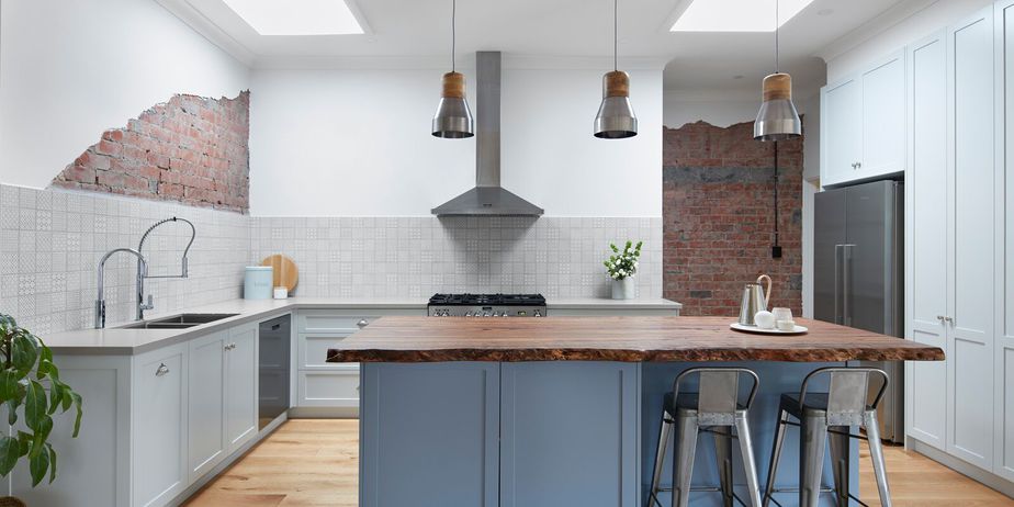 Smarter Bathrooms and Kitchens - a modern kitchen design with wooden floor, kitchen cabinet in the middle with wooden top, beautiful kitchen wall tiles, and unique open brick layer on some parts of the kitchen wall. Beautiful kitchen designs built by kitchen renovation Melbourne specialist